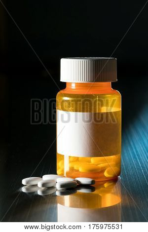Prescription bottle with blank label for copy space and white pills or tablets on metal table for opioid epidemic illustration