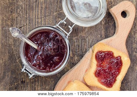 Toasts with strawberry jam for breakfast on rusric wooden background. Top view.