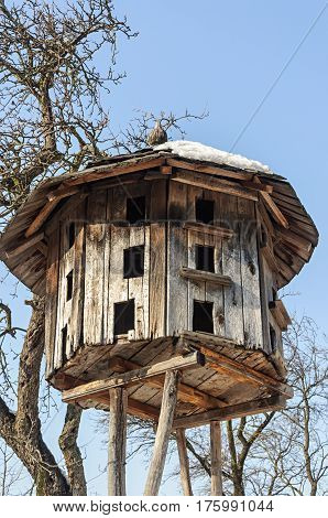 Old wooden dovecote on blue sky background sunny winter day