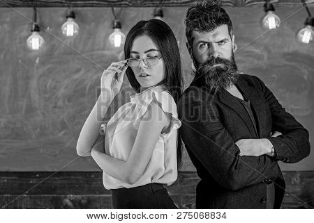 Man With Beard And Teacher In Eyeglasses Stand Back To Back, Chalkboard On Background. Teamwork Conc