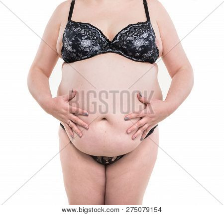 Healthcare, Medical And Overweight Concept. Overweight Woman Measuring Her Fat Belly On A White Back