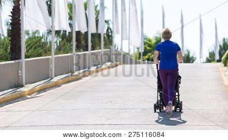 young healthy mother jogging while pushing a baby stroller at city park