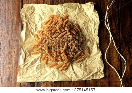 Top View Of The Whole Mass Of Fusilli, On Paper, On A Wooden Background