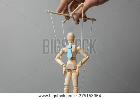 Businessman Leader In Tie On Gray Background. Deryannaya Doll On The Threads That Pulls The Puppetee