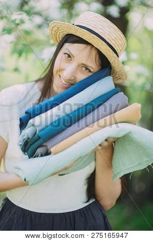 Cropped Image Of Smiling Seamstress Holding Stack Of Colored Fabric