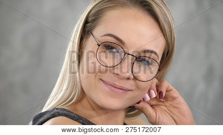 Happy Young Woman Looking At Someone With Smile On Grey Background.