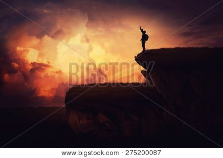 Surreal View As A Young Man With A Backpack Raising Hands Up Celebrating Victory On The Top Of A Hil