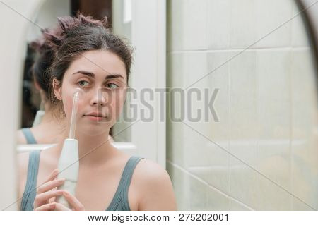 An Attractive Girl Uses A Darsonval Device Against Acne .cares For Skin From Youth.