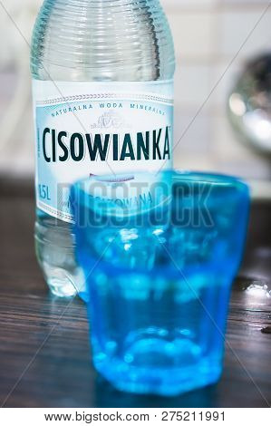Poznan, Poland - November 10, 2018: Polish Cisowianka Water In A Bottle With Blue Glass In Soft Focu