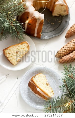 Pie With Raisins And Icing From Powdered Sugar On The Background Of Fir Branches And Garlands. Rusti