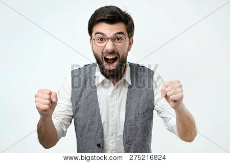 Mature Hispanic Man Is Happy With His Win. He Is Holding His Fists And Shout Wow.
