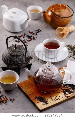 Tea Card. Variety Of Teapots On A Gray Background, Different Types Of Tea. Tea Still Life.
