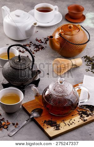 Tea Card. Variety Of Teapots On A Gray Background And Different Types Of Tea. Tea Still Life.