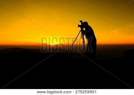 Silhouette Photographer take photo on hill high mountain / Man silhouette photographer and professional camera shooting photo landscape sunset on top mountain  nature twilight yellow sky background