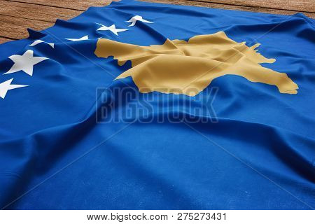 Flag Of Kosovo On A Wooden Desk Background. Silk Kosovar Flag Top View.