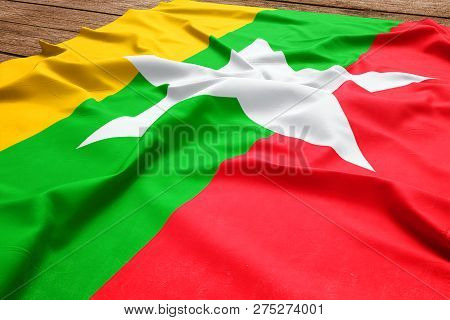 Flag Of Myanmar (burma) On A Wooden Desk Background. Silk Burmese Flag Top View.