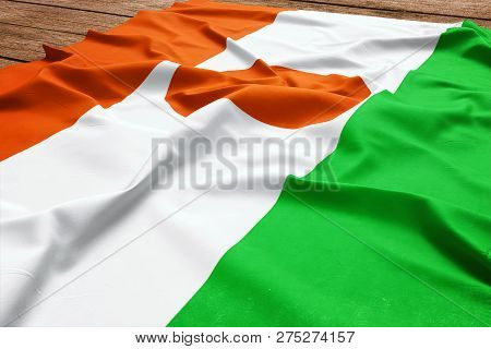 Flag Of Niger On A Wooden Desk Background. Silk Nigerien Flag Top View.