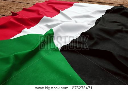 Flag Of Sudan On A Wooden Desk Background. Silk Sudanese Flag Top View.