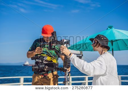 Steadicam Operator And His Assistant Prepare Camera And 3-axis Stabilizer-gimbal For A Commercial Sh