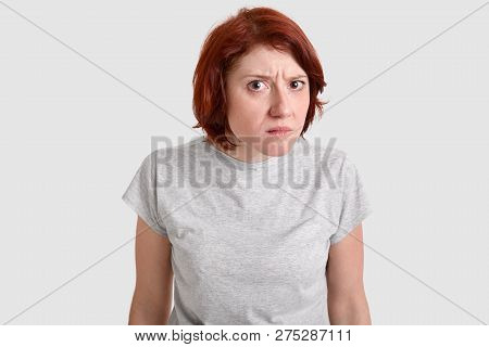 Photo Of Beautiful Redhead Woman Looks With Curious Gaze, Bewilderment At Camera, Wears Casual T Shi