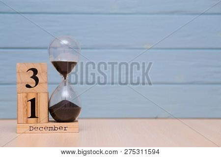 December 31St Set On Wooden Calendar And Hourglass With Blue Background.