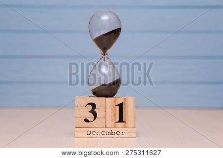 December 31St Set On Wooden Calendar And Hourglass With Blue Background.