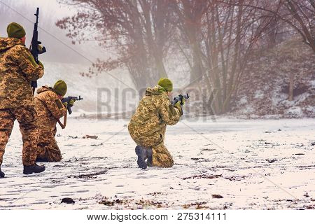 Three Militant Soldiers Conduct Aimed Fire In A Training Camp In The Winter With Automatic Weapons.