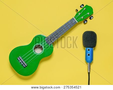 Ukulele Ukulele Ukulele And Wired Blue Microphone On Yellow Background. The View From The Top.