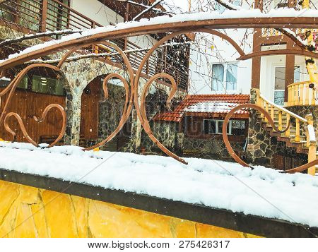 Srone Gate With Decorative Steel Trim. Snowfall On The Street.noon.