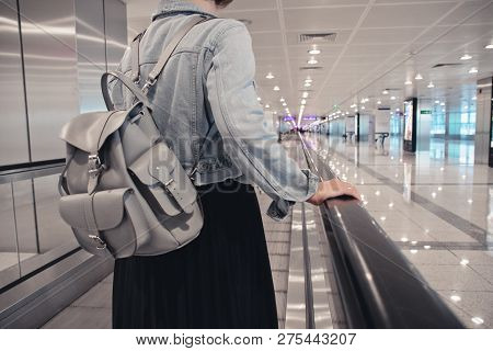 The Girl Is Riding On The Travolator At The Airport With A Laptop. Toned