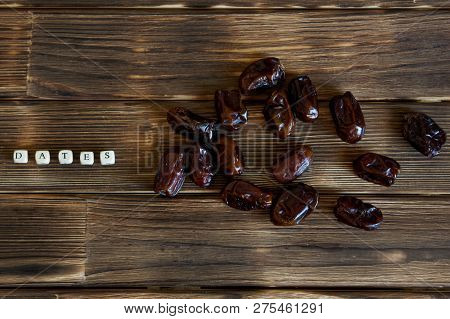 Dried Dates Lie On A Wooden Table, Next To The Explanatory Inscription. View From Above. High-calori