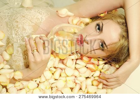 Portrait Of Atrractive Sensual Young Blond Bride With Red Lips Lying In Bath Tub Full Of Water And M