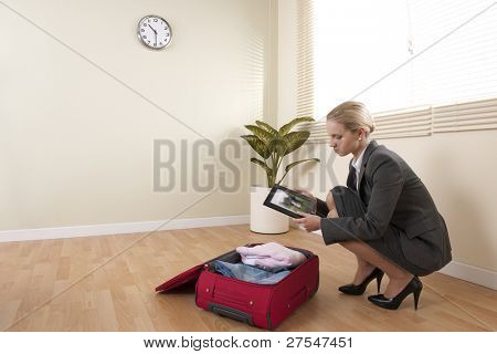 Podnikatelka při přípravě svého zavazadla businesstrip při pohledu na rodinný portrét