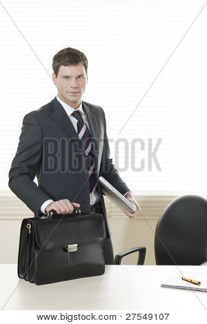 Businessman in his office with briefcase