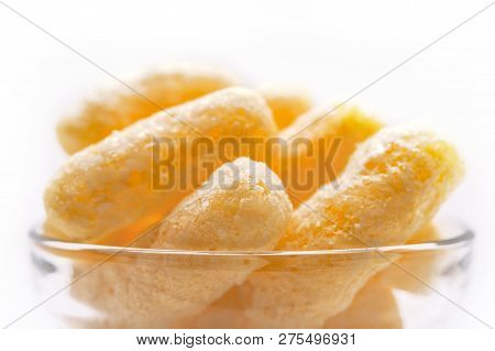 Yellow Corn Puffs In A Glass Bowl. Crunchy Flavored Puffed Snacks. Party, Movie, Tv, Game Snacks.