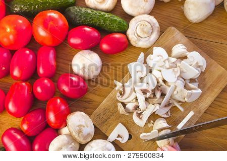 Womans Hands Is Cutting Mushrooms Champignons On The Wooden Bord On Kitchen Table.