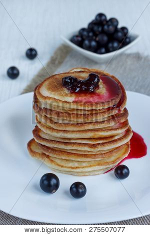 Stack Of American Pancakes With Blackcurrant Jam. Fresh Blackcurrant Are Lying On A White Plate.