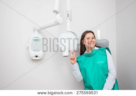 Joyful Beautiful Woman In The Dental Clinic Is Preparing For An X-ray. Diagnostics In Dentistry