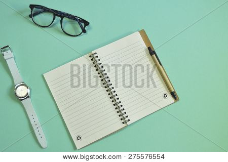 Workplace, Notebook, Watch, Glasses On Mint Background
Diary, Clock, Pen, Glasses On The Table