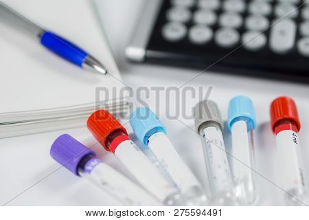 Medicine Bottles For Samples Next To Calculator And Notebook In Hospital Or Laboratory, Closeup On W