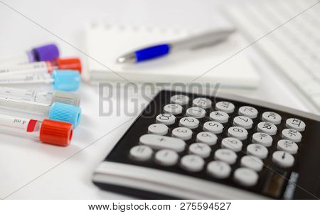Medicine Bottles For Samples Next To Calculator And Notebook In Hospital Or Laboratory, Closeup On W