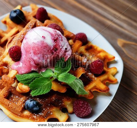 Plate of belgian waffles with ice cream and fresh berries - raspberries and blueberries
