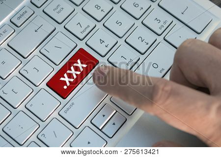 Xxx Button On Keyboard. A Male Finger Presses A Color Button On A Gray Silver Keyboard A Modern Lapt