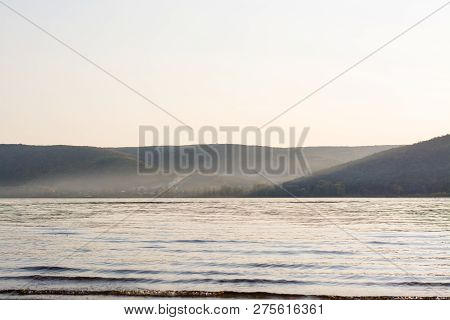 Evening Landscape: Mountains In The Sunset Haze, A Wide River And A Village At The Foot Of The Mount