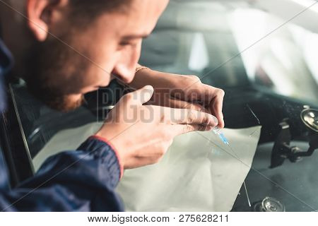 Close-up Of A Professional Windshield Repairman Fills A Crack In The Glass With A Special Polymer Th
