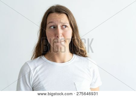 Embarrassed Young Woman Pursing Mouth. Lady Looking Away. Bewilderment Concept. Isolated Front View 