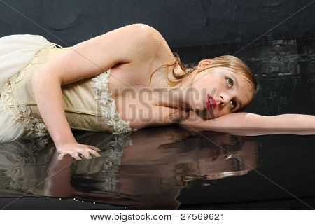 beautiful thoughtful girl wearing in dress with corset lies on wet floor