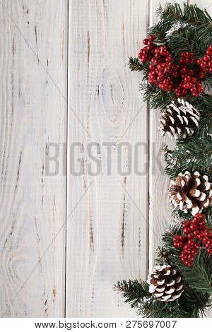 Spruce Branches, Cones And Red Berries On A White Wooden Background. Background For Christmas And Ne