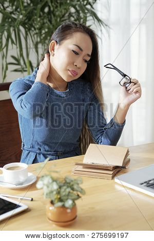 Young Asian Woman Suffering From Pain In Her Neck After Working All Day Long