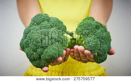 The Concept Of Raw Food. Woman Holding A Bunch Of Green, Raw Broccoli. A Pair Of Green Cabbage Close